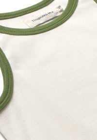 White tank top with green ribbed neckline, featuring a textured fabric. Label reads "THINKING MU" on the inside collar.