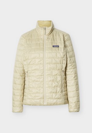 Svetlo béžová prešívaná bunda Patagonia s celopredným zipsom, stojacím golierom a bočnými vreckami so zipsom na jednoduchom pozadí.