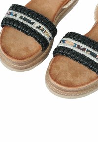 Sandali neri con cinturini intrecciati, caratterizzati da un motivo con perline colorate e una soletta in pelle marrone strutturata. Suola platform con design intrecciato.