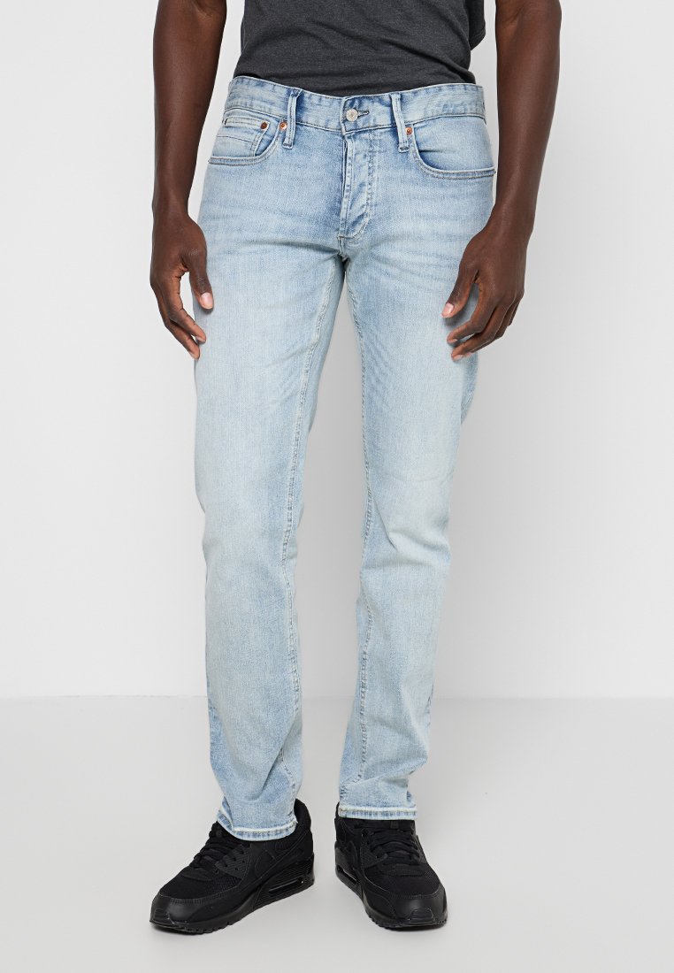 Lichtblauwe denim jeans met een fitted vorm, vijf-pocket ontwerp en tonale stiksels. Gedirigeerd met een donker t-shirt en zwarte sneakers.