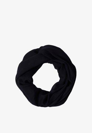 Femme portant une casquette jaune, un t-shirt gris à manches courtes, une écharpe bleue autour du cou et un jean bleu, regardant légèrement sur le côté.