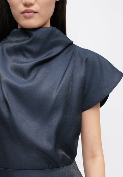 Satin navy top med høj krave og flagrende ærmer, med en glat tekstur og subtil glans, som sidder tæt til kroppen.