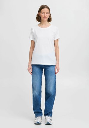 Hvit bomull T-skjorte med rund hals, sammen med lyseblå rette jeans og grå-hvite joggesko. En enkel, uformell antrekk.