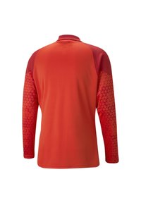 Langärmliges Sportoberteil in leuchtendem Rot mit kontrastierenden, strukturierten Ärmeln, die ein gradienten Dreiecksmuster aufweisen. Lässige Passform mit Kragen.
