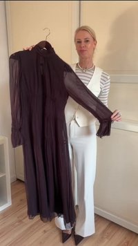 Rochie lungă, transparentă, de culoare mov închis, cu guler înalt și textură plisată. Mâneci lungi terminate cu manșete cu volane. Atârnă pe un cârlig.