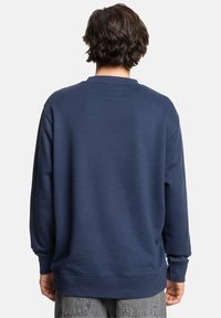 Navy blue sweatshirt with a rounded neckline, long sleeves, and ribbed cuffs. Soft fabric with a smooth texture. No visible logos or patterns.