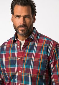 Camicia a quadri in rosso, blu e arancione con colletto a bottoni. Presenta una tasca sul petto e colori contrastanti in un motivo a griglia.
