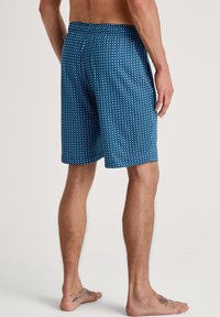 Blauwe gebloemde shorts met kleine witte vierkanten, elastische tailleband, knielange snit en lichtgewicht stof. Geen zichtbare zakken.