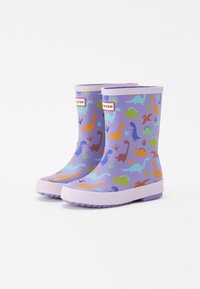 Violet lasten sade-saappaat, joissa on värikkäitä dinosaurusten kuvastoja ja valkoiset pohjat, seisovat vierekkäin valkoista taustaa vasten.