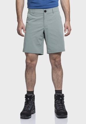 Hellgraue Wandershorts aus strapazierfähigem Material, mit Knopfverschluss, seitlichen Taschen und geradem Bein. Kombiniert mit schwarzen Wanderschuhen.