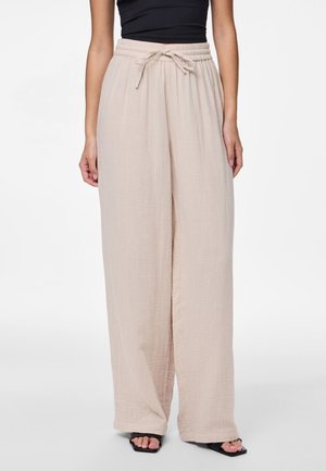 Pantalons larges beiges avec une taille élastique et un cordon de serrage. Fabriqués dans un tissu texturé et léger, avec une coupe ample.