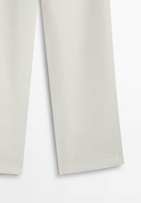 Pantalons larges gris clair avec une texture lisse et une finition soignée. Présentent un ourlet avec des détails de couture minimalistes.