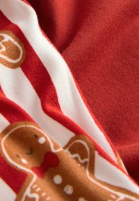 Rood-wit gestreepte stof met een ontwerp van een peperkoekkoekje met een glimlachend gezicht en een rode strik, zachte textuur en warme kleurenpalet.