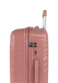 Maleta rígida en color rosa mate con ranuras horizontales, doble cremallera, cerradura de combinación integrada y asa retráctil plateada.