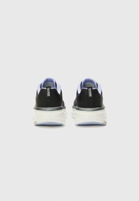 Scarpe sportive nere con suola bianca, dotate di tomaia in mesh, colletto imbottito e dettagli riflettenti sul tallone, progettate per comfort e supporto.