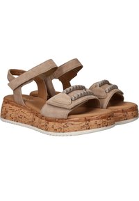 Beige suède sandalen met crossoverbandjes, decoratieve metalen accenten en een kurken plateauzool. Textuurrijke witte rubberen buitenzool.