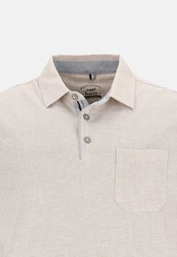 Kortsleeve beige polo med krage, treknappslucka, bröstficka och diskret textur. Grå detaljer på kragen och knappsluckan.