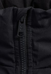 Svart dragkedja i tyg, närbild som visar den släta texturen, synliga sömmar och en robust dragkedja med en minimalistisk design.