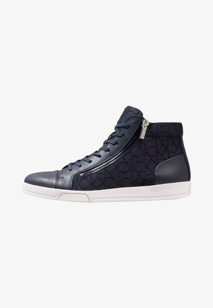 Zapatilla deportiva alta de color azul marino con patrón de logo CK en relieve, cremallera lateral, cordones y suela blanca con la marca Calvin Klein.