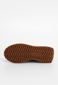 Semelle de chaussure avec motif de bande de roulement en zigzag marron et logo U.S. Polo Assn. embossé au centre.