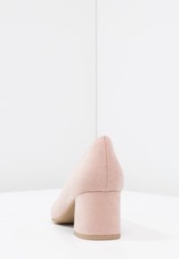 Scarpa con tacco quadro in suede rosa, dalla punta affusolata. Texture liscia, design minimalista e un tacco più largo e stabile per un supporto aggiuntivo.