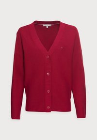 Röd cardigan av stickad kvalitet, med V-ringning, långa ärmar och knäppning fram, samt logotyp på övre vänstra sidan.