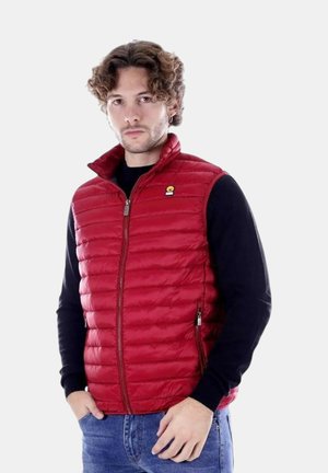 Gilet imbottito rosso con colletto alto, chiusura a zip e tasche laterali. Presenta una piccola etichetta con logo sul petto. Indossato sopra una maglietta nera a maniche lunghe.