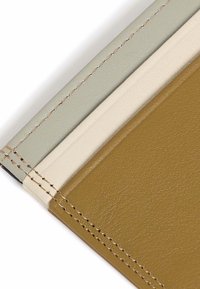 Cubierta de cuaderno de cuero en tres colores: verde claro, crema y marrón. Presenta costuras visibles a lo largo de los bordes para mayor durabilidad.