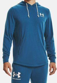 Felpa con cappuccio blu realizzata in tessuto morbido, con tasca frontale, cappuccio con cordino e logo Under Armour bianco sul petto.