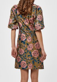 Vestido floral con mangas abullonadas que presenta un fondo dorado y rosas rosas bordadas con hojas verdes. La vista posterior resalta la textura de la tela.