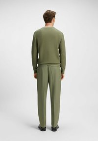 Green knitted sweater with a textured pattern, paired with matching tailored trousers. Both items exhibit a smooth finish and slim fit.