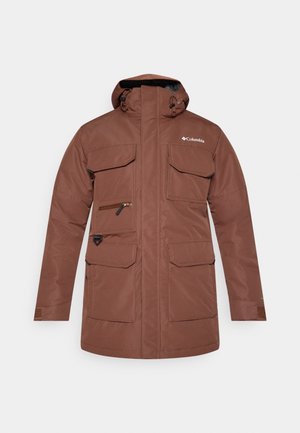 Bruine waterdichte jas met een hoge kraag, een afneembare capuchon, meerdere voorzakken en een ritszak op de borst. Voorzien van verstelbare manchetten.