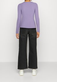 Paars ribbed shirt met lange mouwen en een ronde halslijn, gecombineerd met hoge taille wijde zwarte jeans en witte sneakers.