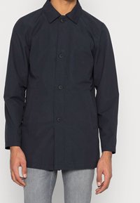 Marinblå lättviktsjacka med klassisk krage, framknäppning, två sidofickor och raglanärmar för en avslappnad passform.