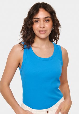 Blaues geripptes Tanktop mit rundem Ausschnitt und breiten Schulterträgern. Das Model trägt es mit hellen Hosen, um die Passform des Tops zu präsentieren.