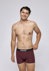 Bordové boxerky s černým pasem a bílým logem "SNOCKS", těsně padnoucí, hladký povrch a bez viditelných vzorů.