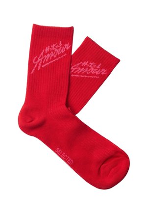 Par røde ankelsokker med ribbet mansjett, med en rosa skriftslogo nær toppen og teksten "SELECTED" på sålen.