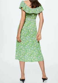 Robe midi florale verte avec un décolleté volanté à épaules dénudées, un corsage ajusté et une jupe évasée. Le tissu a une texture lisse avec des motifs vibrants.