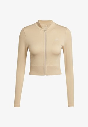 Beige kort zip-jacka i mjukt tyg, med långa ärmar, hög krage och subtila texturerade detaljer på axlarna.
