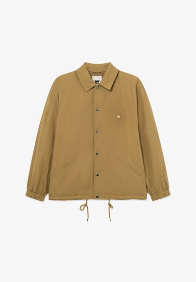 Veste boutonnée marron clair avec col, poignets élastiques, deux poches avant inclinées, cordon de serrage ajustable à l'ourlet et petit patch logo sur le côté gauche de la poitrine.