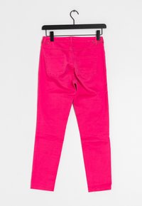 Rosa Denim-Hose mit schmaler Passform, ausgestattet mit zwei Gesäßtaschen und Gürtelschlaufen, hängend an einem schwarzen Kleiderbügel vor einem weißen Hintergrund.