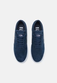 Ναυτικά μπλε σουέτ αθλητικά παπούτσια με λευκές ελαστικές σόλες. Διαθέτουν στρογγυλές μύτες, σχέδιο με κορδόνια και υφή στην επάνω πλευρά για καλύτερη πρόσφυση. Διακριτική λεπτομέρεια με branding.