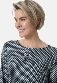 Marinebluse mit geometrischem Muster in Hellblau, rundem Ausschnitt und einem kleinen Knopfdetails vorne. Weicher Stoff.