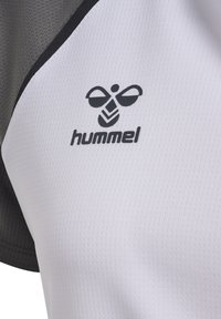 Logo d'abeille Hummel en noir et blanc imprimé sur un tissu sportif texturé blanc et gris.