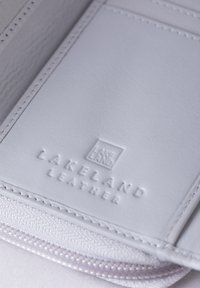 White leather wallet interior featuring embossed "Lakeland Leather" logo, smooth texture, and contrasting stitching details.