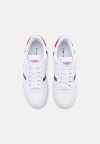 Hvite lær sneakers med teksturert finish, med marineblå og røde detaljer, snøring og en logo på siden.