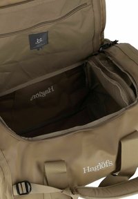 Borsa da viaggio marrone con una texture liscia, numerose tasche con cerniera e un'etichetta con logo. Presenta manici robusti e compartimenti interni per l'organizzazione.