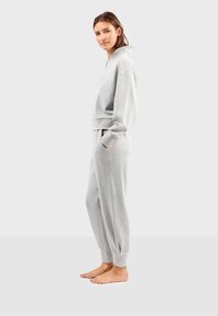 Grijze katoenen sweatshirt met hoge kraag, gecombineerd met bijpassende tapered broek met elastische manchetten en zijzakken.