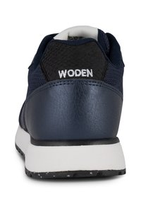 Zapatos deportivos de color navy con un upper de malla negra texturizada, acentos de cuero suave, costuras blancas y una suela contrastante en blanco y negro.