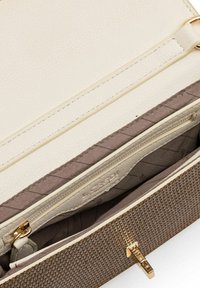 Getextureerde beige en crèmekleurige handtas binnenkant, met een ritsvak en een gepatineerd stoffen voering, voorzien van accenten in goudkleurig hardware.